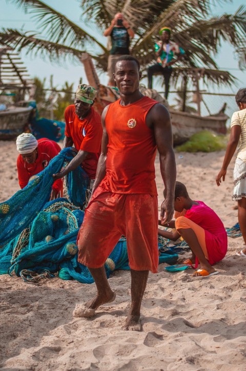 man wearing orange tank top standing near green coconut tree