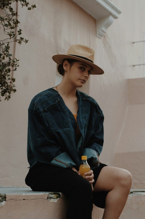 a woman sitting on a ledge with a bottle of orange juice