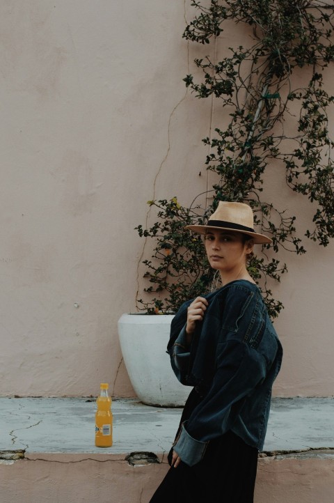 a woman standing next to a wall wearing a hat KyZdBk