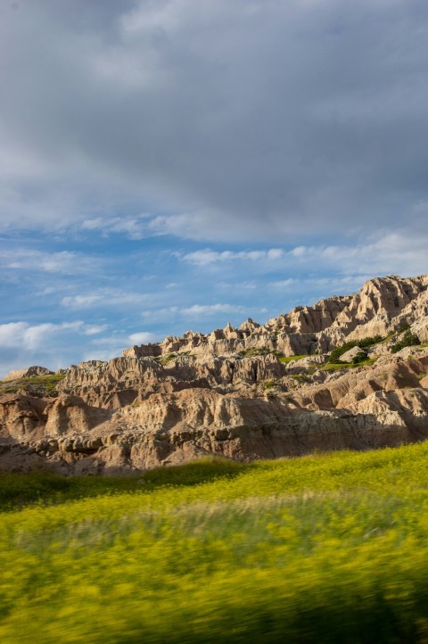 a field of green grass and rocks under a cloudy sky