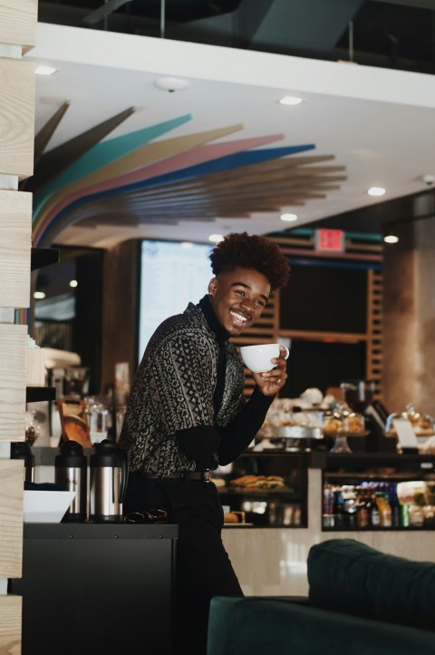 man standing holding white teacup rKV