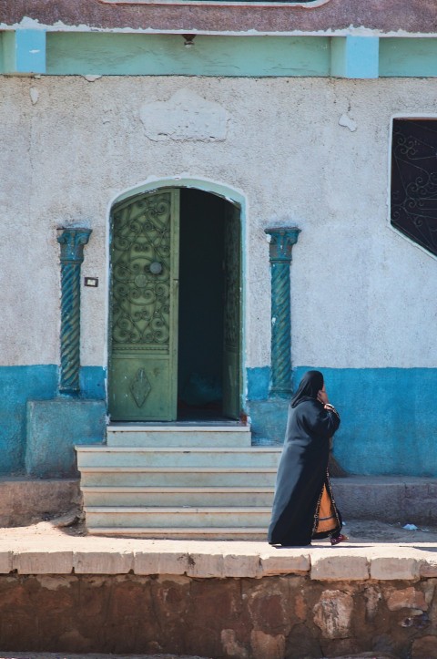 a woman walking down a street past a building