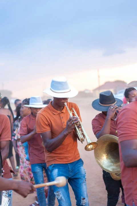 man in blue polo shirt playing trumpet during daytime