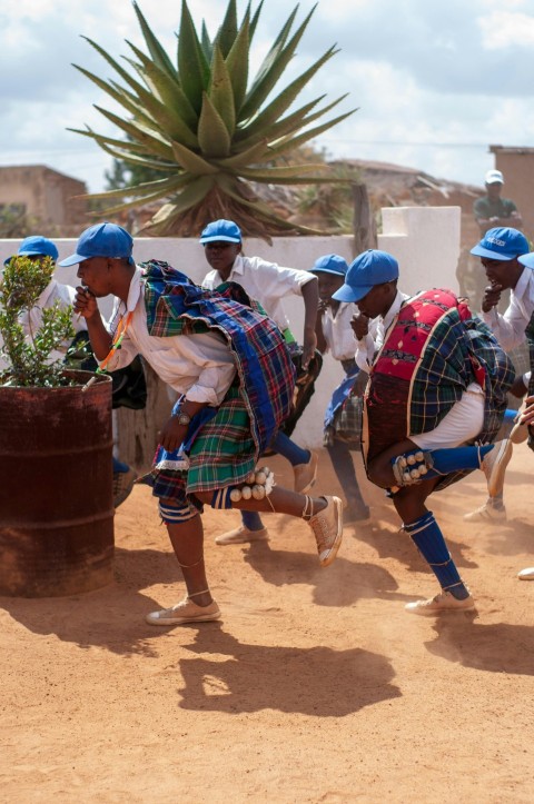 people in traditional dress sitting on brown wooden barrel during daytime