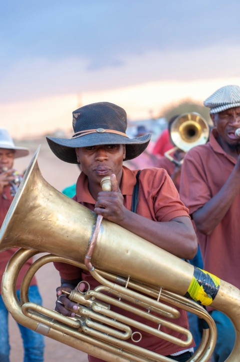 man in red coat and brown cowboy hat playing trumpet