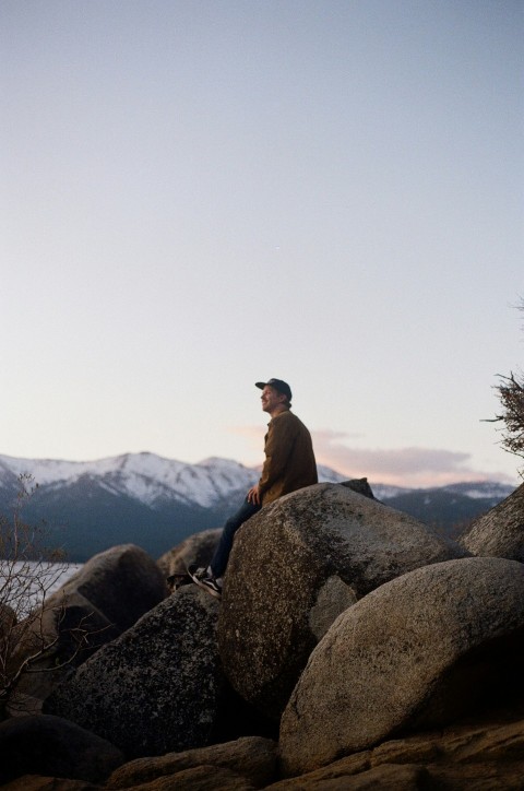 a man sitting on top of a large rock