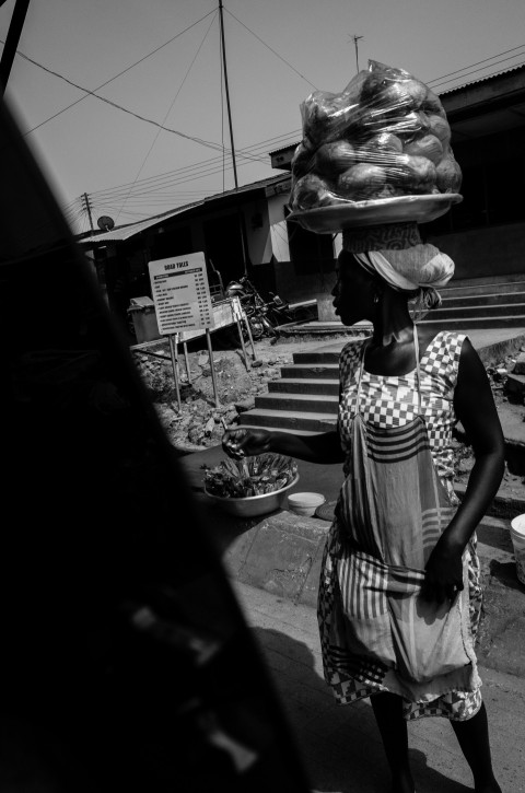 grayscale photo of woman in black and white stripe dress standing near table