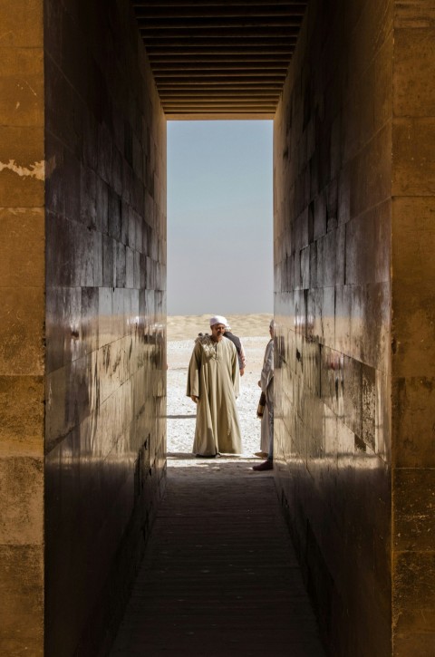 woman in white robe standing on gray concrete pathway during daytime