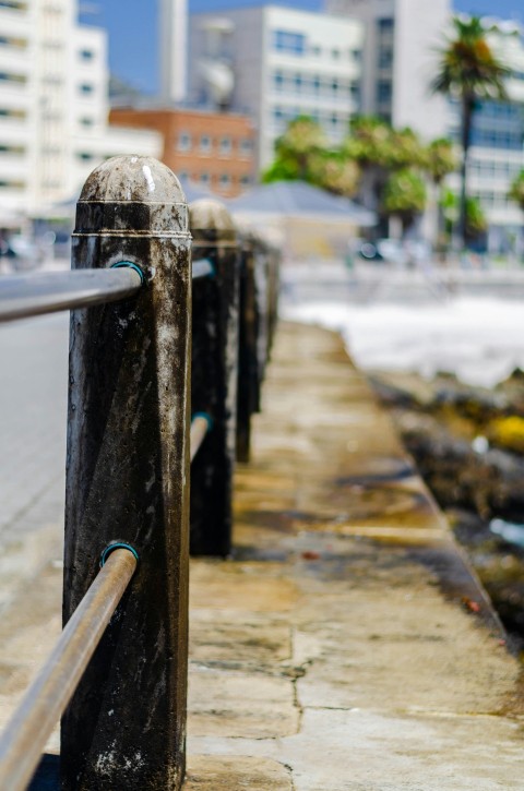 a metal fence next to the ocean with buildings in the background q4 gIY5l