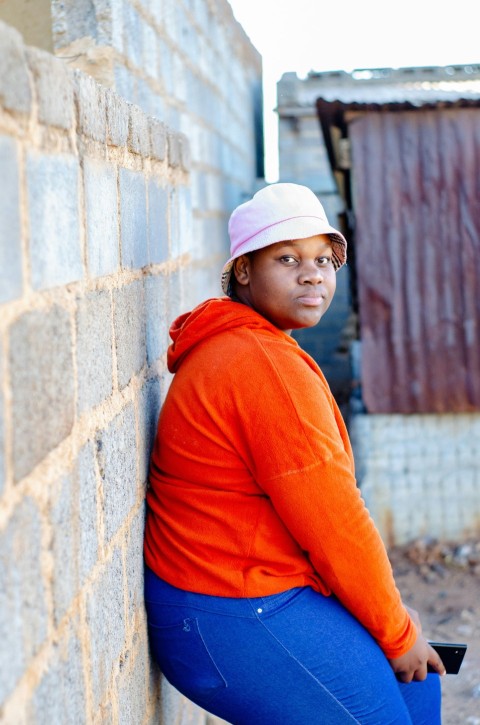 a woman leaning against a brick wall