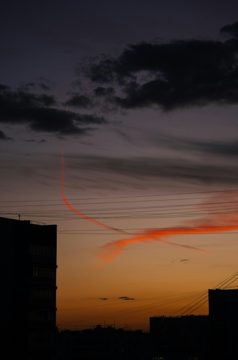 a sunset view of some buildings and a plane in the sky