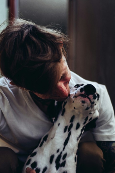 woman in white shirt hugging dalmatian dog