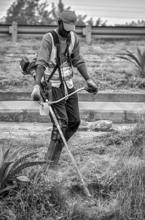 grayscale photo of man in black jacket and pants holding stick