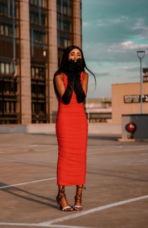 a woman in a red dress standing in a parking lot uPW8