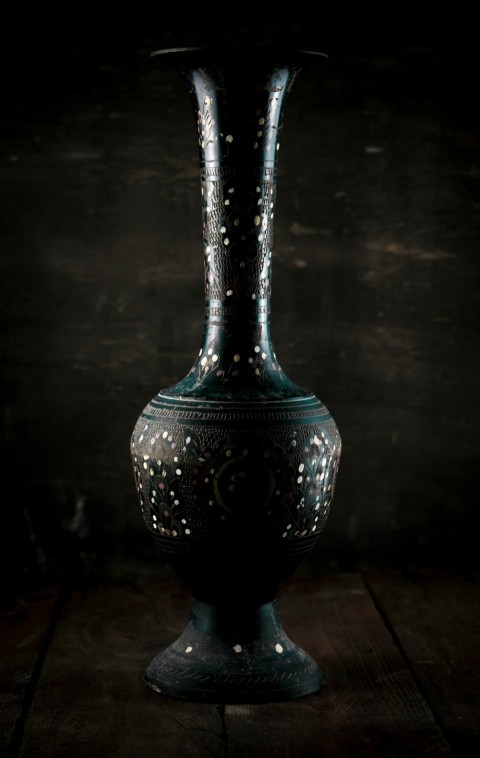 a black vase sitting on top of a wooden table