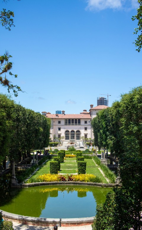 a large building with a garden and a pond in front of it