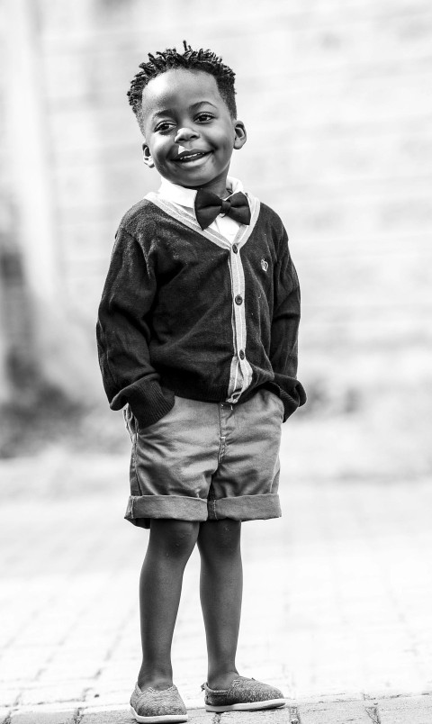 grayscale photo of boy in black button up cardigan and shorts