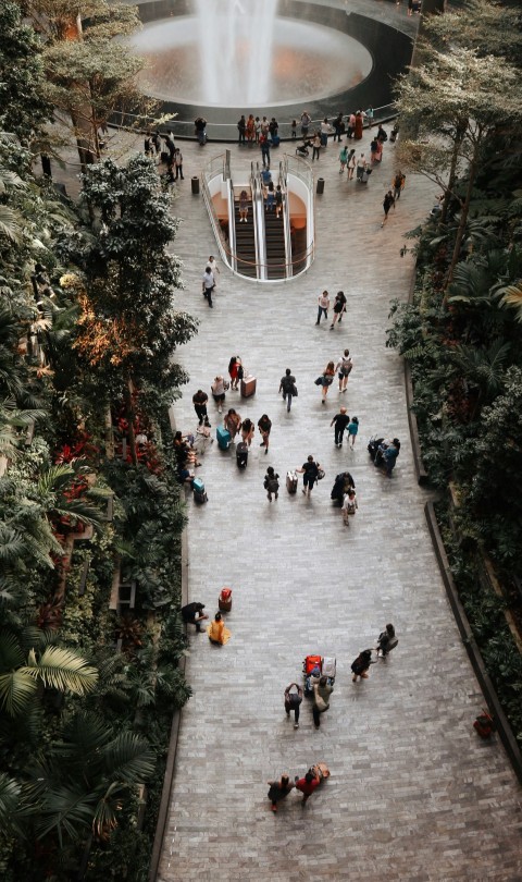 crowd walking inside airport with waterfalls