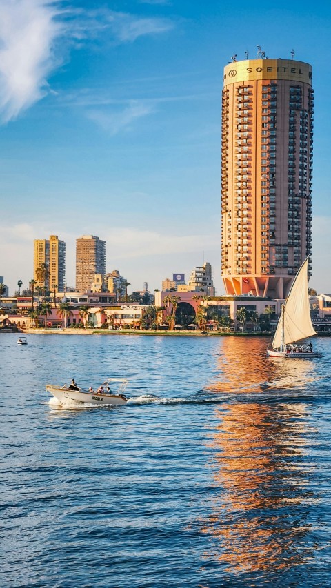 a sailboat in the water near a tall building