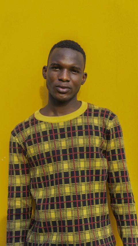 a man standing in front of a yellow wall