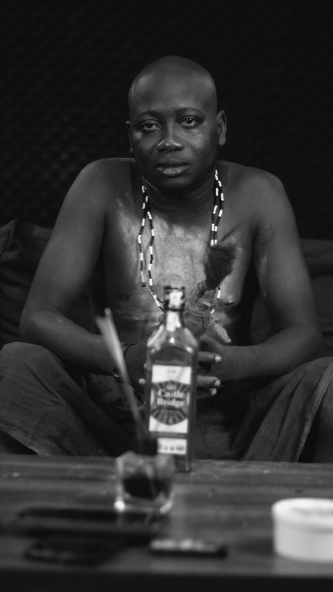 a man sitting on a couch in front of a bottle UsZdwtb