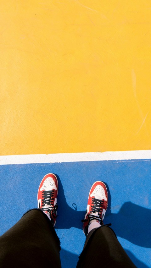 a person standing on a blue and yellow tennis court