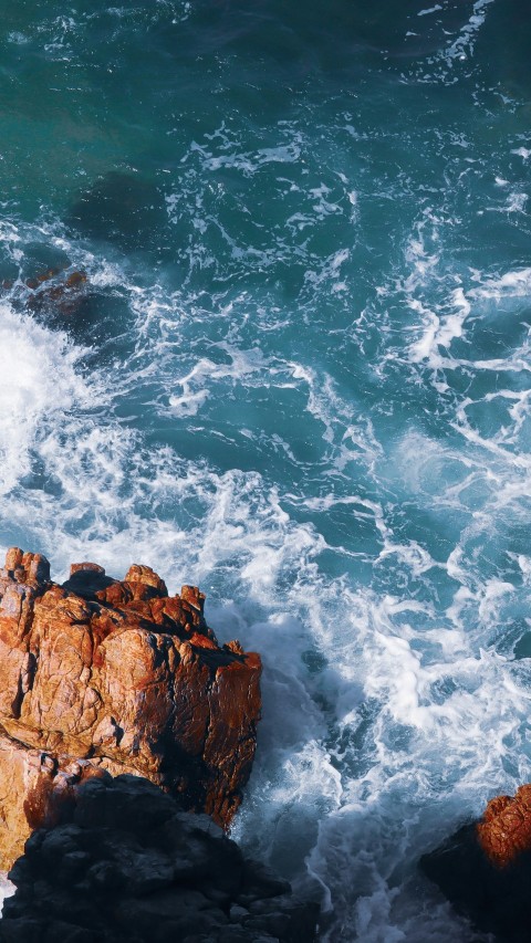 brown rocky mountain beside ocean waves during daytime DXpqa