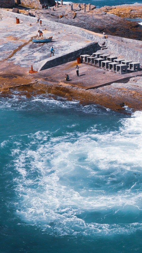 people standing on brown rock formation near body of water during daytime