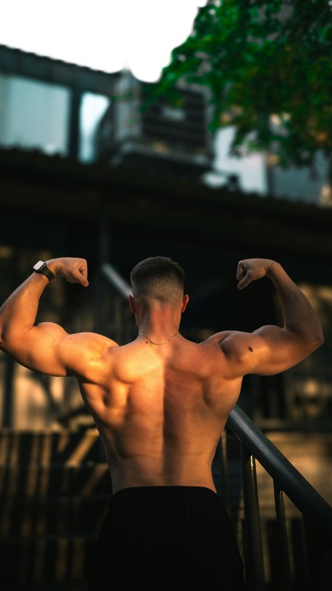 a man flexing his muscles on a balcony