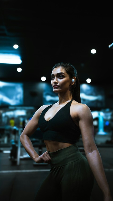 a woman standing in a gym with her hands on her hips