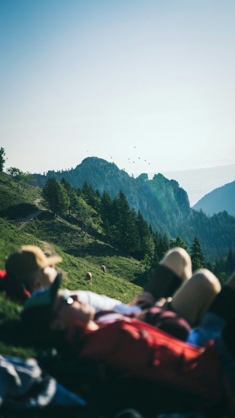 two people lying on green field viewing mountain during daytime MhSg_Q