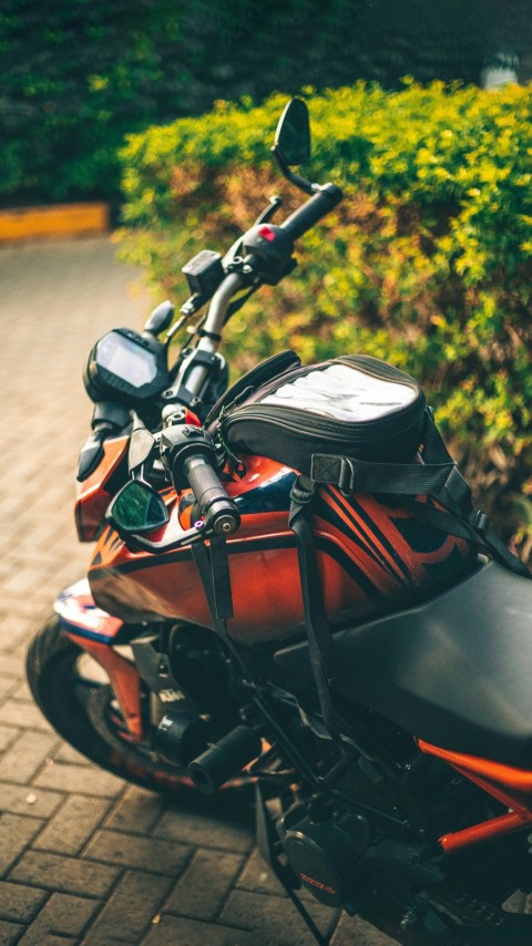 a red and black motorcycle parked on a brick road