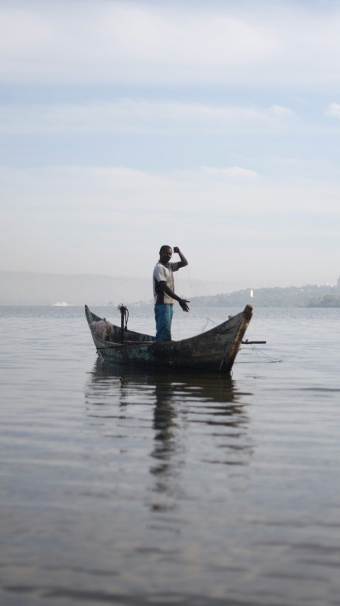 a man standing in a boat on a lake