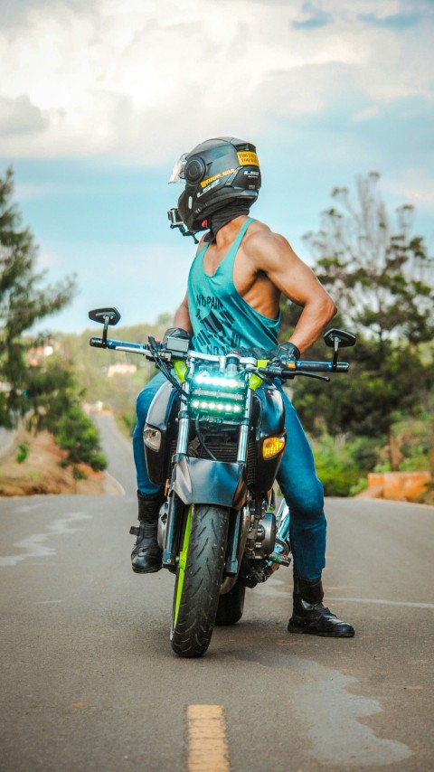 a man riding on the back of a motorcycle down a road