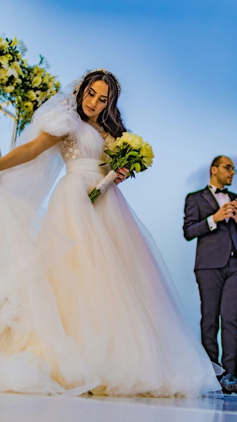 a woman in a wedding dress holding a bouquet of flowers