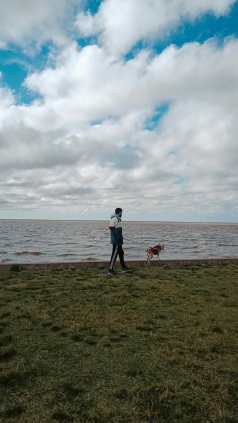 a man walking a dog on a leash next to a body of water