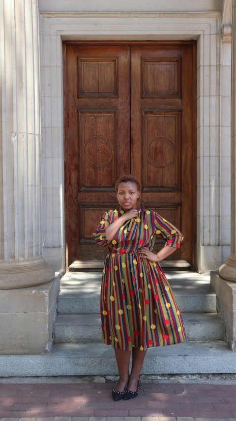 woman standing outdoors in front of a closed wooden door