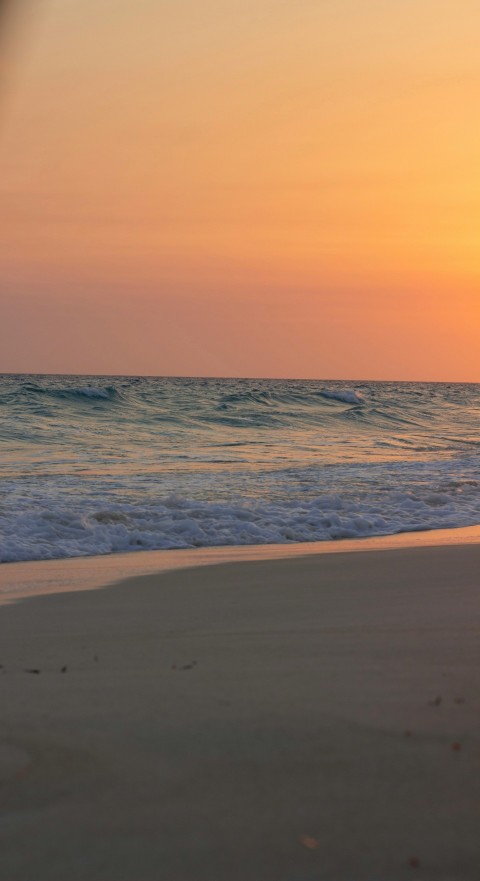 a person walking on the beach with a surfboard