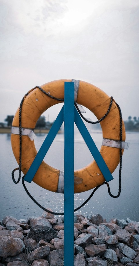 orange lifebuoy hanging on post near water