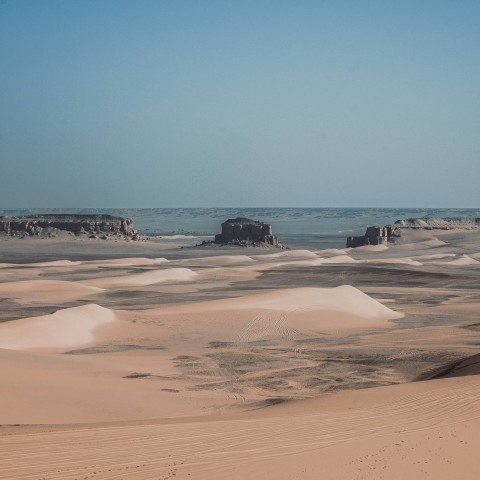 a sandy area with a few rocks in the distance