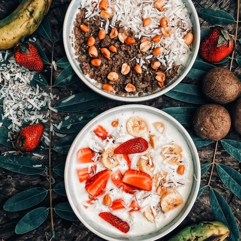 two bowls of cereal and fruit on a table