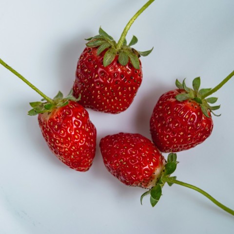 a group of three strawberries sitting on top of a white table