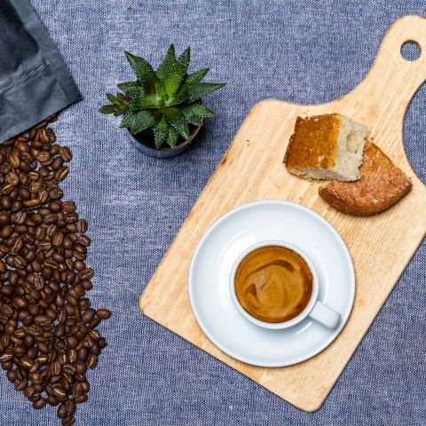 white ceramic cup on white ceramic saucer beside brown wooden chopping board