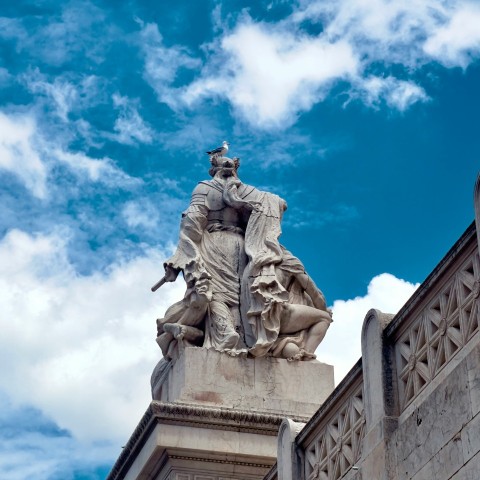 a statue of a man holding a gun on top of a building Ng4vL1AHR