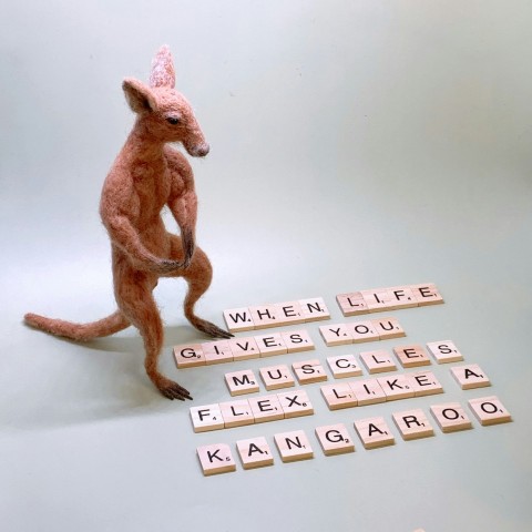 a toy kangaroo standing on its hind legs next to scrabble letters