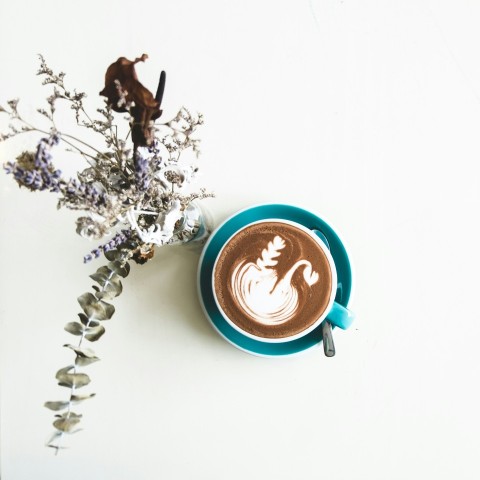 chocolate latte in cup beside flowers in vase d