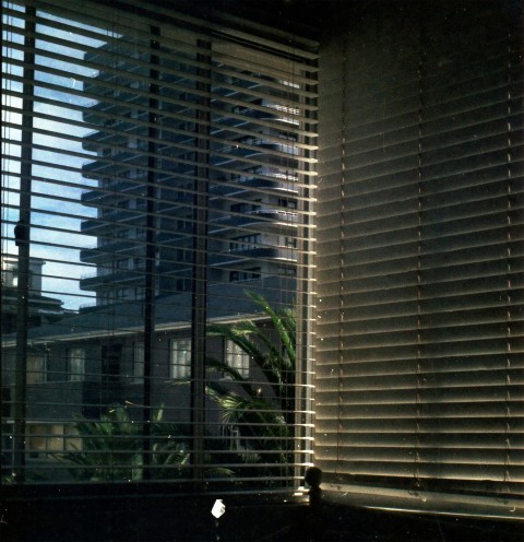 a view of a building through the blinds of a window