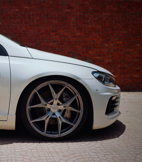 white car parked beside brown brick wall