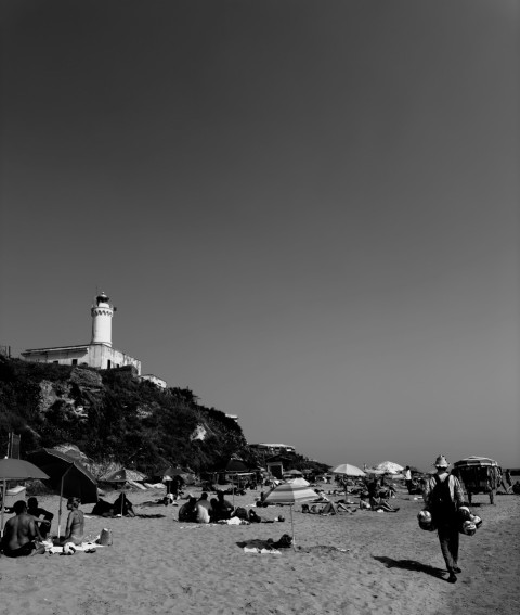 a black and white photo of people on a beach T0FWA3R