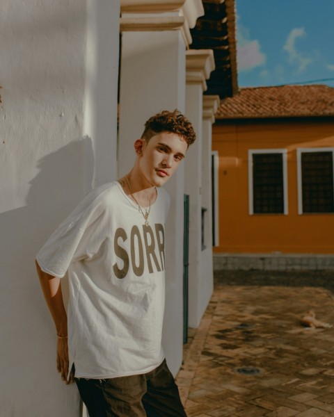 man in white and blue crew neck t shirt standing near white wall during daytime